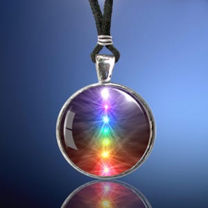 May include: A silver pendant necklace with a round glass charm featuring a colorful chakra symbol. The charm has a rainbow of colors with a white light radiating from the center.