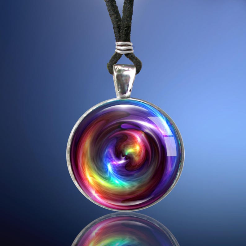 May include: A silver pendant necklace with a round, colorful, swirling design. The pendant features a rainbow of colors, including red, orange, yellow, green, blue, indigo, and violet. The necklace is on a black cord.