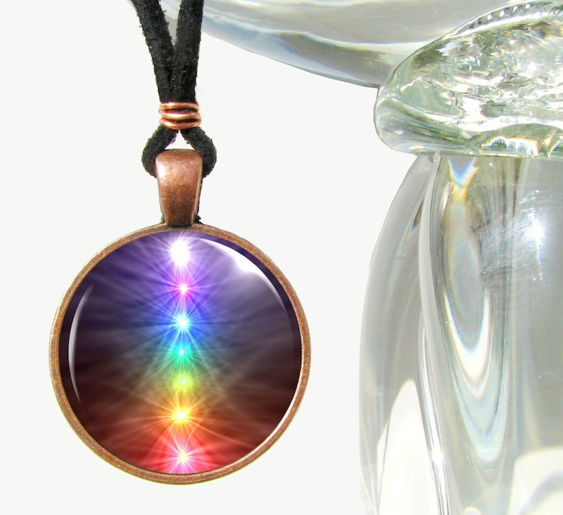 May include: A copper pendant necklace with a round glass charm featuring a colorful chakra symbol. The charm has a dark background with seven glowing chakras in rainbow colors.