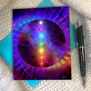 May include: A rectangular print featuring a central dark sphere surrounded by a vibrant purple and blue radial burst pattern. Seven glowing, vertically aligned points of light in rainbow colors are visible within the sphere. A black pen is placed nearby.
