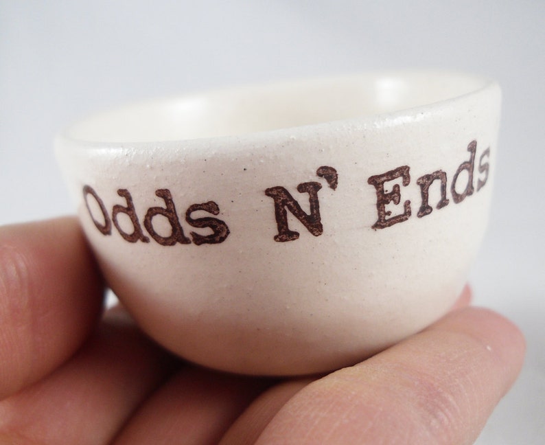 May include: White ceramic bowl with the words "Odds N' Ends" printed in brown lettering.