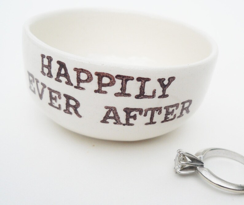 May include: White ceramic ring dish with the words "Happily Ever After" in brown lettering.