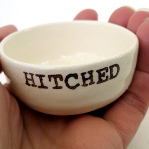 May include: White ceramic dish with the word "HITCHED" written in black lettering.