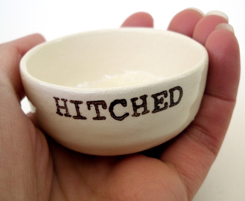 May include: White ceramic dish with the word "HITCHED" written in black lettering.