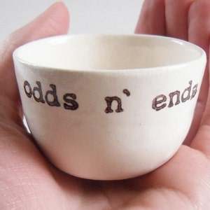 May include: White ceramic bowl with the words "odds n' ends" written in brown lettering.