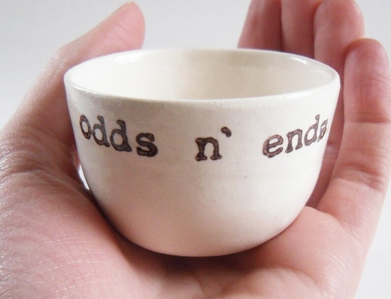 May include: White ceramic bowl with the words "odds n' ends" written in brown lettering.