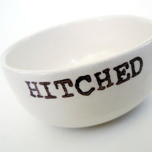 May include: White ceramic bowl with the word "HITCHED" printed in brown lettering.