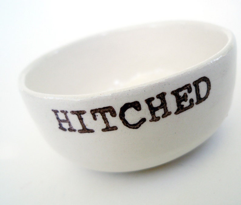 May include: White ceramic bowl with the word "HITCHED" printed in brown lettering.