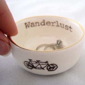 tandem bicycle ceramic wedding ring dish or engagement ring holder, printed with wanderlust text with a gold or silver rim, add custom color