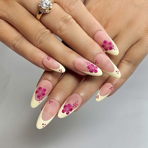 Unhas postiças elegantes com ponta francesa floral rosa | Desenhos de flores brancas e fúcsia pintados à mão | Manicure personalizada em formato amendoado longo