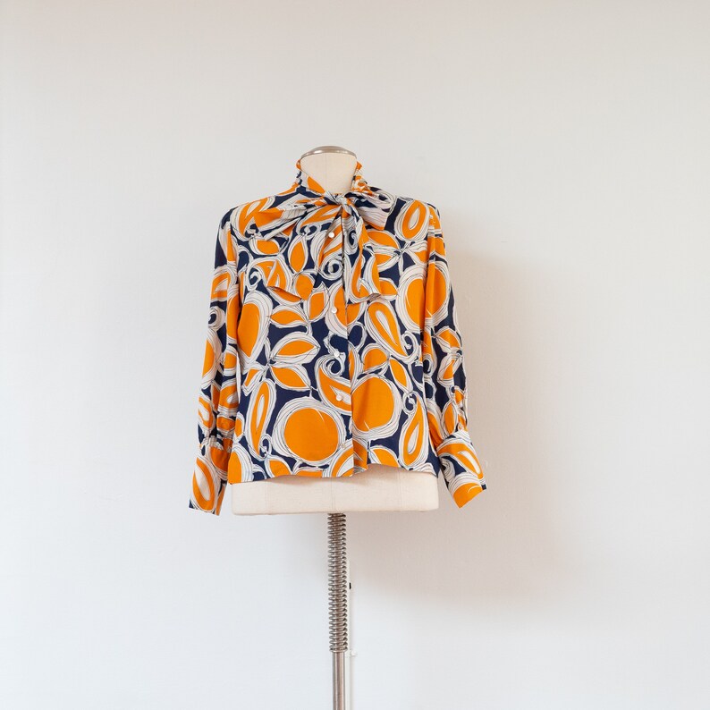 ML 1970s orange and blue abstract blouse 70s vintage pussy bow draped button-front rayon shirt with abstract floral print