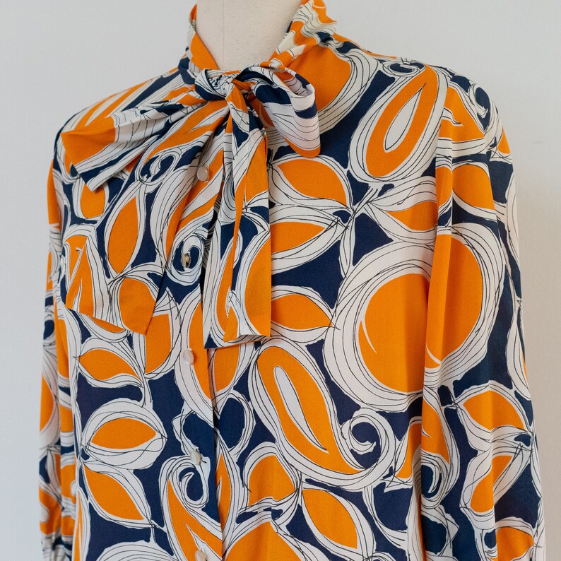 ML 1970s orange and blue abstract blouse 70s vintage pussy bow draped button-front rayon shirt with abstract floral print