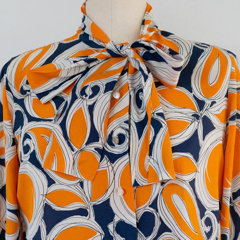 ML 1970s orange and blue abstract blouse 70s vintage pussy bow draped button-front rayon shirt with abstract floral print