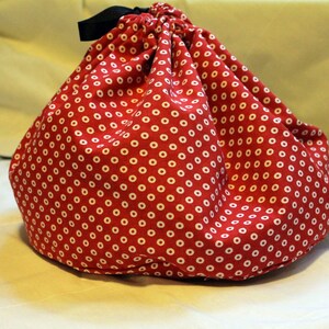 May include: A red drawstring bag with white polka dots. The bag is made of fabric and has a black drawstring.