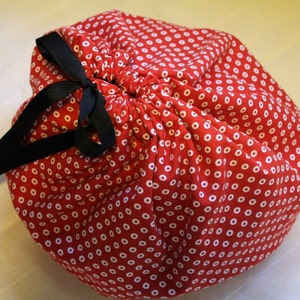 May include: A red drawstring bag with white polka dots and a black ribbon tie.