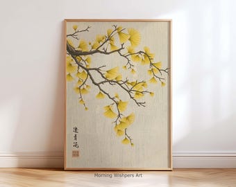 Könnte beinhalten: Gerahmter Kunstdruck mit einem Ast mit gelben Ginkgoblättern und braunen Ästen vor beigem Hintergrund. Das Kunstwerk hat eine asiatische Ästhetik mit japanischen Schriftzeichen und einem roten Siegel in der unteren linken Ecke.