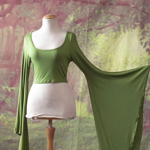 Peut inclure: Un haut court vert à manches longues et larges manches bouffantes. Le haut est fait d'un tissu doux et extensible et a un col rond.