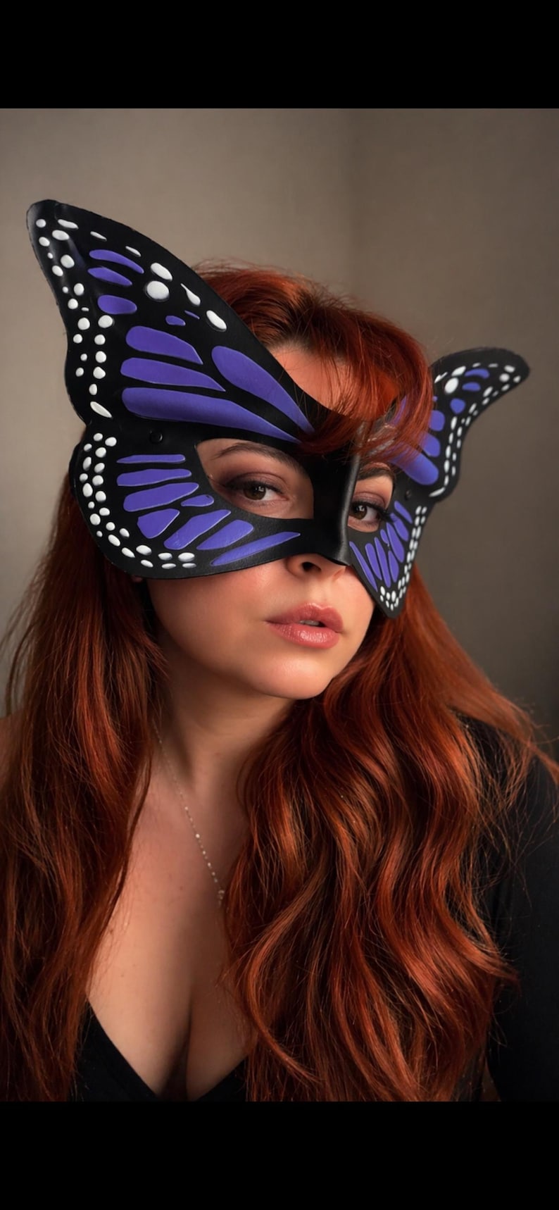 May include: A black butterfly mask with purple and white detailing. The mask features a butterfly wing design and is worn over the eyes. The mask is made of a smooth material, a costume accessory.