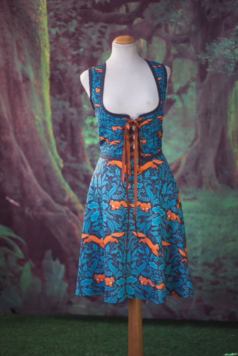 May include: A blue and orange dress with a floral pattern and brown ribbon lacing. The dress is on a mannequin against a green and brown background.