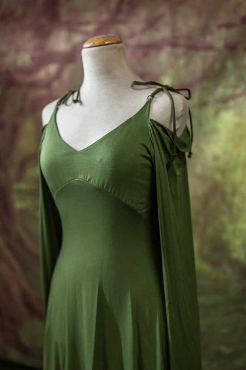 May include: A green sleeveless dress with long sleeves that are tied at the shoulders. The dress has a V-neckline and a flowing skirt.