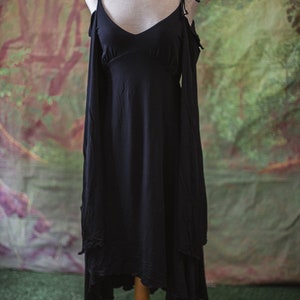 May include: A black sleeveless dress with a V-neckline and a high-low hemline. The dress has a relaxed fit and is made of a soft, flowing fabric.