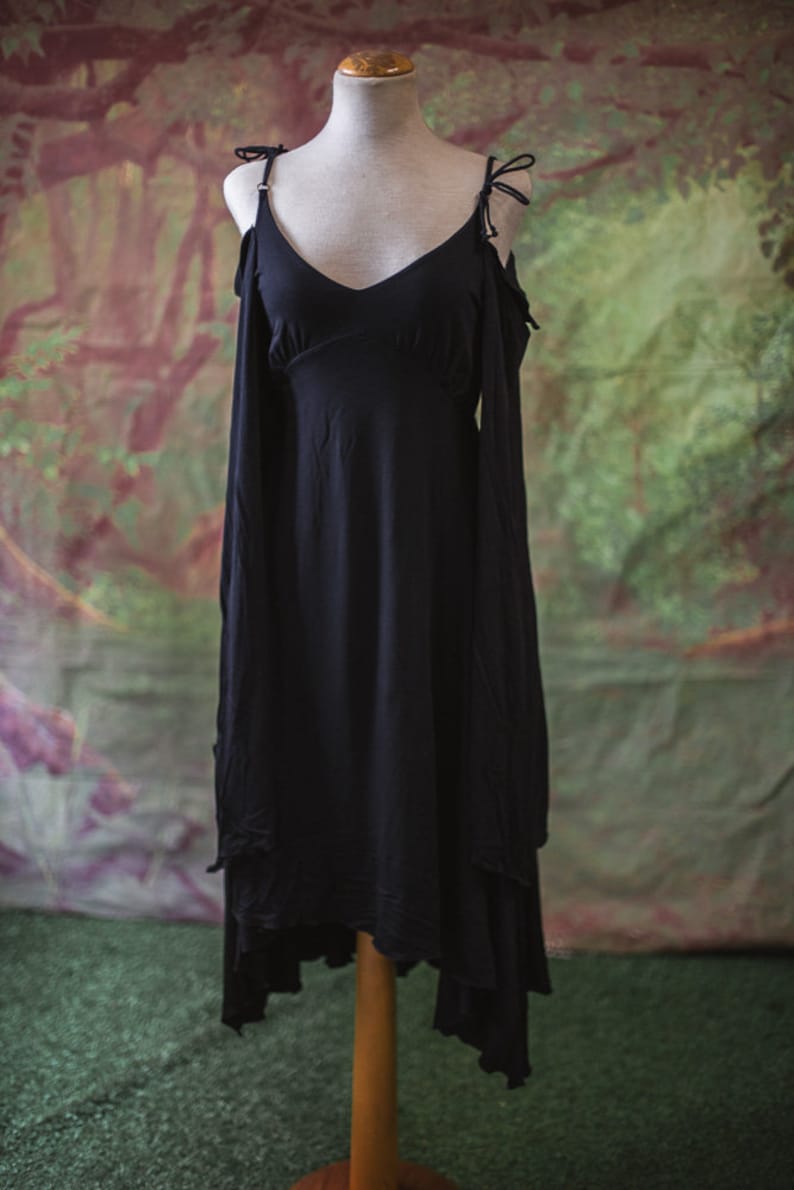 May include: A black sleeveless dress with a V-neckline and a high-low hemline. The dress has a relaxed fit and is made of a soft, flowing fabric.