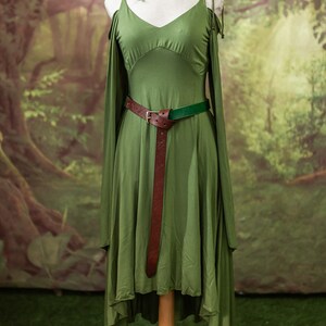 May include: A green dress with a low neckline and a brown leather belt. The dress has a high-low hemline and is made of a soft, flowing fabric.
