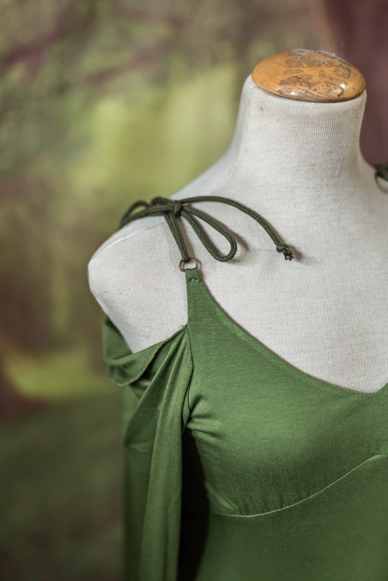 May include: A green off-the-shoulder dress with long sleeves and a tied strap detail.
