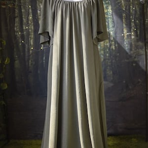 K&ouml;nnte beinhalten: Ein langes, flie&szlig;endes, schulterfreies Kleid in einem ged&auml;mpften Olivgr&uuml;n. Das Kleid ist aus einem weichen, flie&szlig;enden Stoff gefertigt und hat eine lockere Passform.