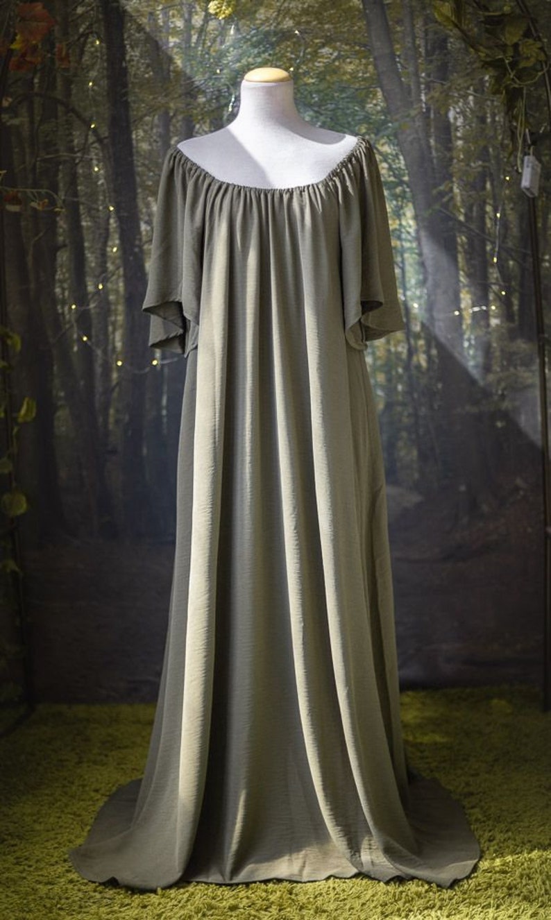 K&ouml;nnte beinhalten: Ein langes, flie&szlig;endes, schulterfreies Kleid in einem ged&auml;mpften Olivgr&uuml;n. Das Kleid ist aus einem weichen, flie&szlig;enden Stoff gefertigt und hat eine lockere Passform.