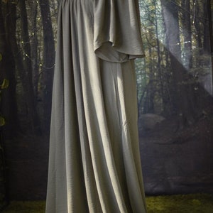 K&ouml;nnte beinhalten: Ein langes, flie&szlig;endes, schulterfreies Kleid in einem ged&auml;mpften Olivgr&uuml;n. Das Kleid ist aus einem weichen, flie&szlig;enden Stoff gefertigt und hat eine lockere Passform.