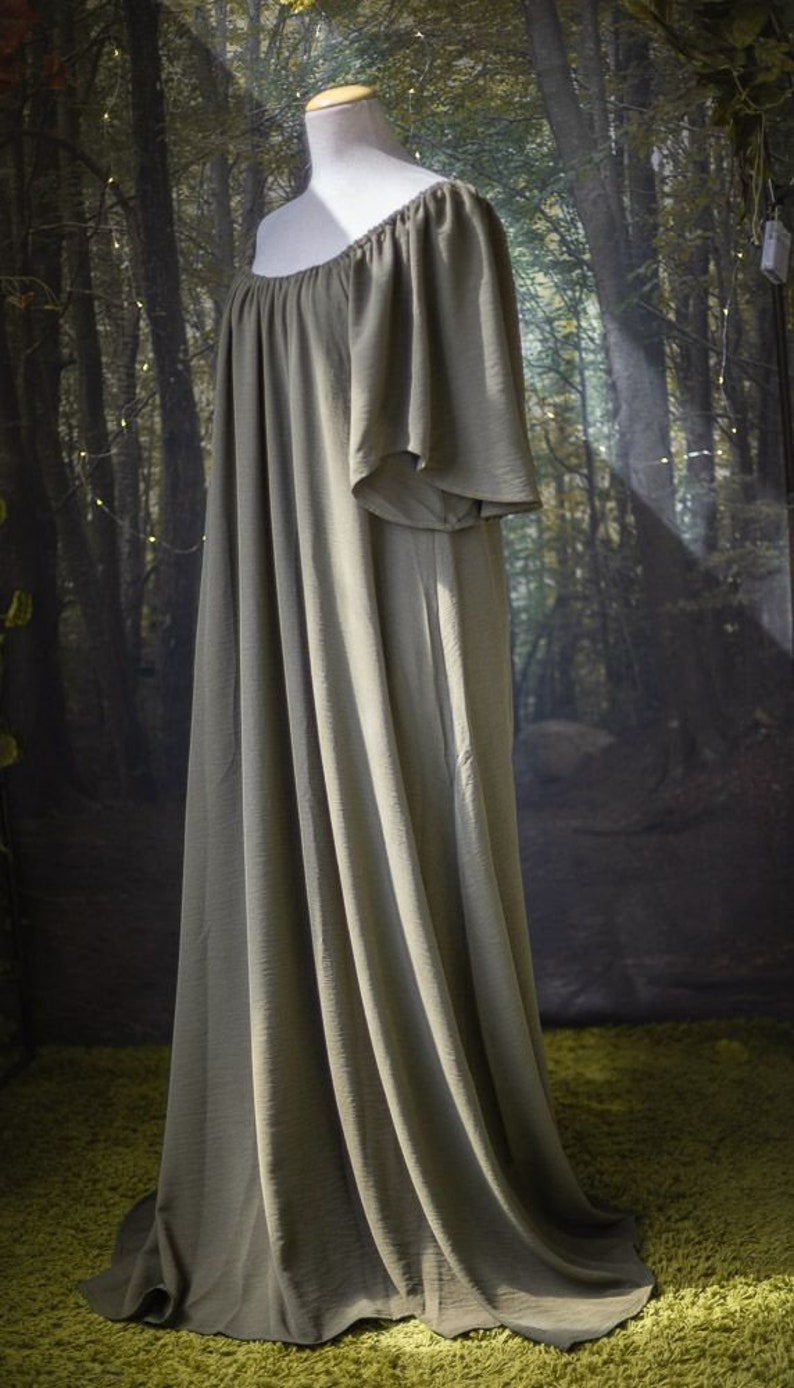 K&ouml;nnte beinhalten: Ein langes, flie&szlig;endes, schulterfreies Kleid in einem ged&auml;mpften Olivgr&uuml;n. Das Kleid ist aus einem weichen, flie&szlig;enden Stoff gefertigt und hat eine lockere Passform.