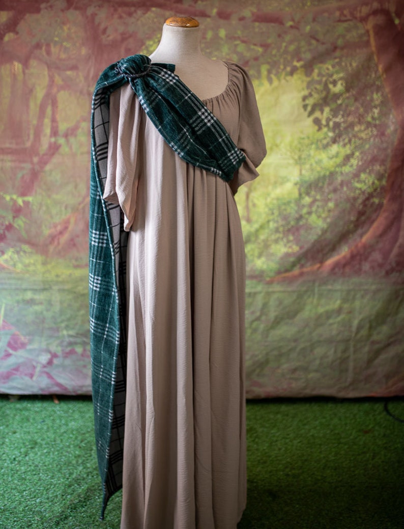 May include: A beige maxi dress with a green and white plaid scarf draped over the shoulder. The scarf is tied in a knot at the neck.