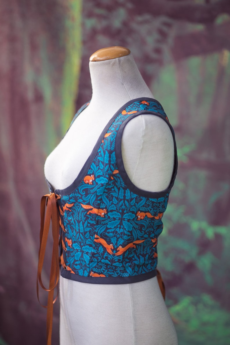 May include: A blue and orange patterned corset with brown lacing. The corset is sleeveless and has a fitted bodice.