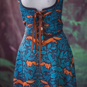 May include: A blue and orange dress with a floral pattern and squirrels. The dress has a brown lace-up bodice and a full skirt.