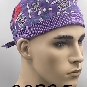 Puede incluir: Un gorro quir&uacute;rgico morado con un ribete de lunares blancos y las palabras "NEURO SURGERY" impresas. El gorro tiene un patr&oacute;n de gr&aacute;ficos de tem&aacute;tica m&eacute;dica y el n&uacute;mero "0273 F" est&aacute; impreso en la parte inferior.