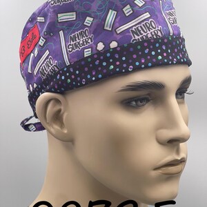 Puede incluir: Un gorro quir&uacute;rgico morado con ribete de lunares negros. El gorro presenta las palabras "NEURO SURGERY" y un patr&oacute;n de mascarillas m&eacute;dicas y l&iacute;neas onduladas. Una etiqueta roja dice "13 Style".