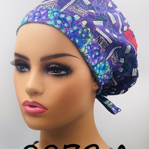 Puede incluir: Un gorro quir&uacute;rgico morado con un patr&oacute;n de instrumentos m&eacute;dicos y las palabras "Neuro Surgery". El gorro tiene un borde con estampado azul y verde. El texto "0273 A" es visible en la parte inferior.