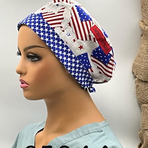 May include: A white, blue, and red patterned scrub cap featuring the American flag and a map of the United States. The cap has a blue star pattern border and a red tag with text. The image also shows the text "0504 A".