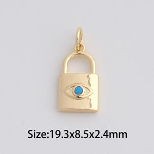 May include: Gold-colored padlock charm with a turquoise eye design. The charm measures 0.76 x 0.33 x 0.09 inches. The charm has a loop at the top for attaching to a necklace or bracelet. The charm is on a white background.