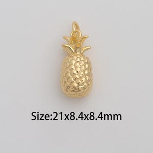 May include: A gold-colored pineapple charm with a textured surface. The charm is 21mm long, 8.4mm wide, and 8.4mm high. The charm has a loop at the top for attaching to a necklace or bracelet.