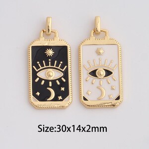May include: Two rectangular pendants with gold-colored frames. One pendant has a black background with a white eye, crescent moon, and starburst design. The other pendant has a white background with a black eye, crescent moon, and starburst design. Each pendant is 30mm x 14mm x 2mm.