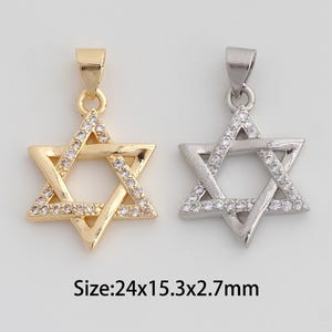 May include: Two Star of David pendants, one gold-toned and one silver-toned, each adorned with small, clear gemstones. The pendants are approximately 0.94 inches long, 0.60 inches wide, and 0.11 inches thick. The text on the image reads: Size:24x15.3x2.7mm.