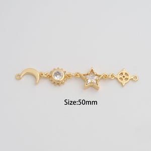 May include: A gold-colored charm featuring a crescent moon, sun, star, and diamond-shaped design. The star has a clear crystal center. The text "Size:50mm" is below the charm.