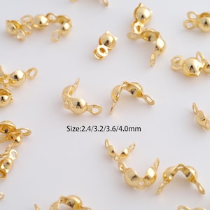 May include: Close-up of several gold-colored jewelry findings. The findings are in various shapes, including curved and rounded designs with small loops. The text "Size: 2.4/3.2/3.6/4.0mm" is visible.