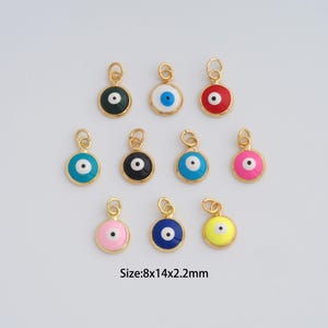 May include: A collection of gold-colored, round charms with an evil eye design. Each charm features a different colored enamel background, including green, white, red, blue, black, and pink, with a white and black eye in the center. The size is 8x14x2.2mm.