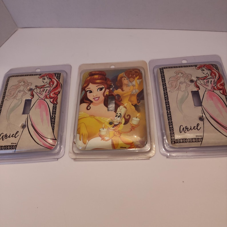 Pu&ograve; includere: Tre coperture decorative per interruttori della luce con personaggi Disney. Una copertura mostra Belle con Lumiere, un'altra Ariel, e la terza mostra anche Ariel. Ogni copertura &egrave; racchiusa in una confezione di plastica trasparente.