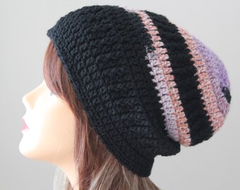 May include: A black crocheted beanie with pink and purple stripes. The beanie is slouchy and has a wide brim.