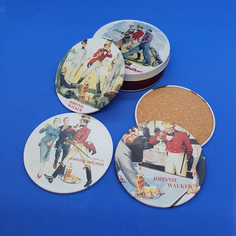 May include: A set of four round coasters and a tin with a vintage illustration. The coasters feature images of people in red coats and the text "JOHNNIE WALKER". The tin has a similar design with the word "Walker".