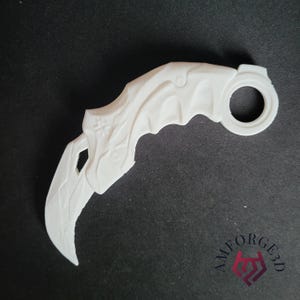 May include: A white karambit knife with a curved blade and a finger ring. The handle has carved details, and the blade has a sharp point. The knife is set against a dark background.